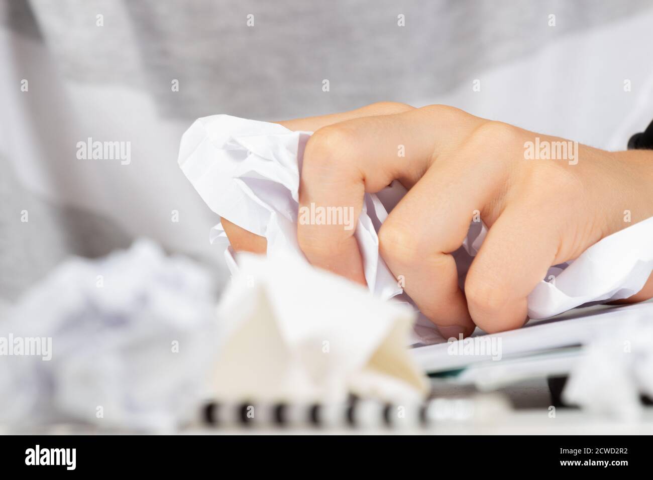 Frustrated hand squeezing a crumpled ball of paper Stock Photo