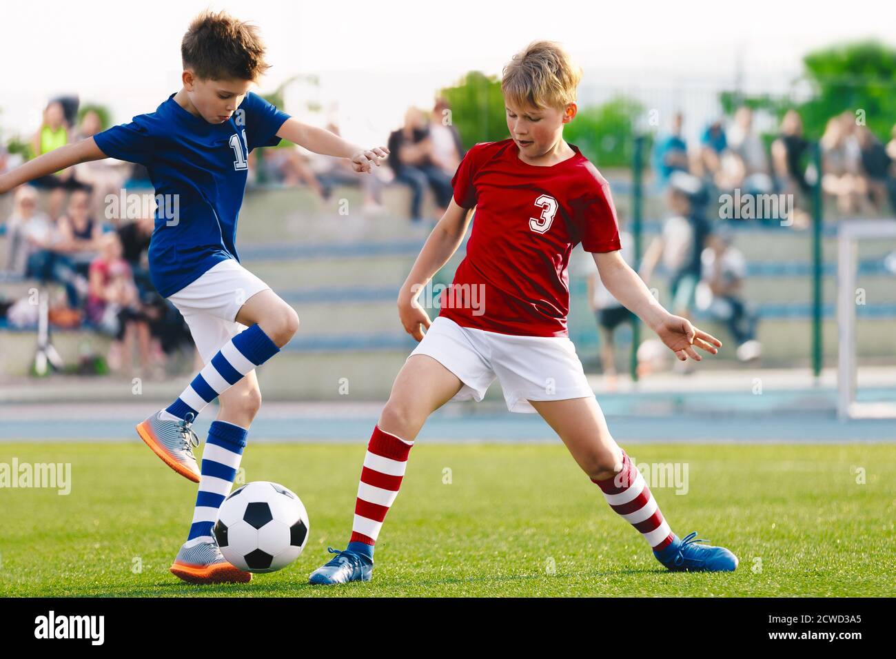 Happy kids compete in football game. Running soccer players. Competition between players running and kicking football ball. Football school. Young boy Stock Photo
