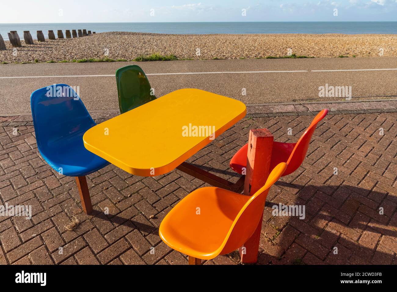 England, East Sussex, Eastbourne, Colourful Empty Cafe Table and Chairs with Beach Stock Photo