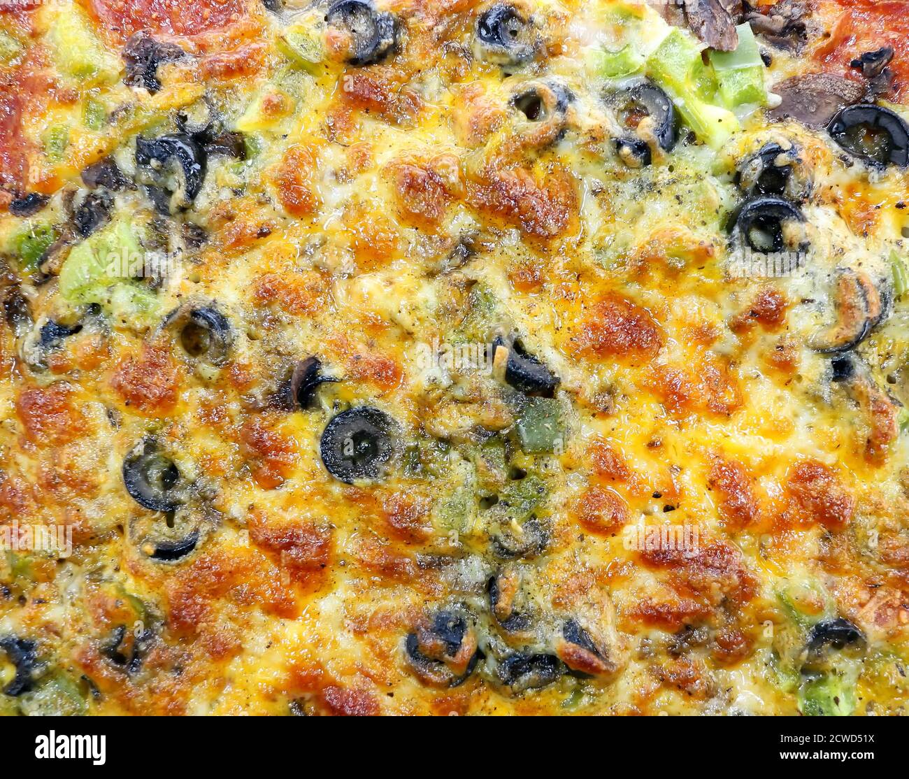 Close up photo of a pizza, topped with, baked cheese, olives, green pepper, sauce,  and pepperoni. Stock Photo