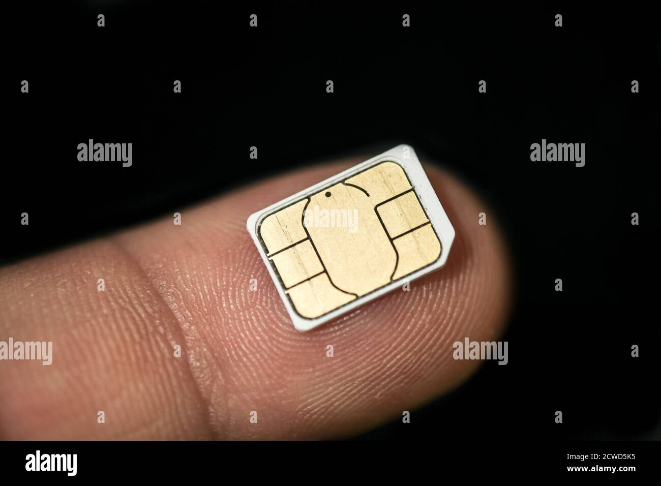 Isolated nano sim card on human finger over black background,hi tech smartphone Stock Photo