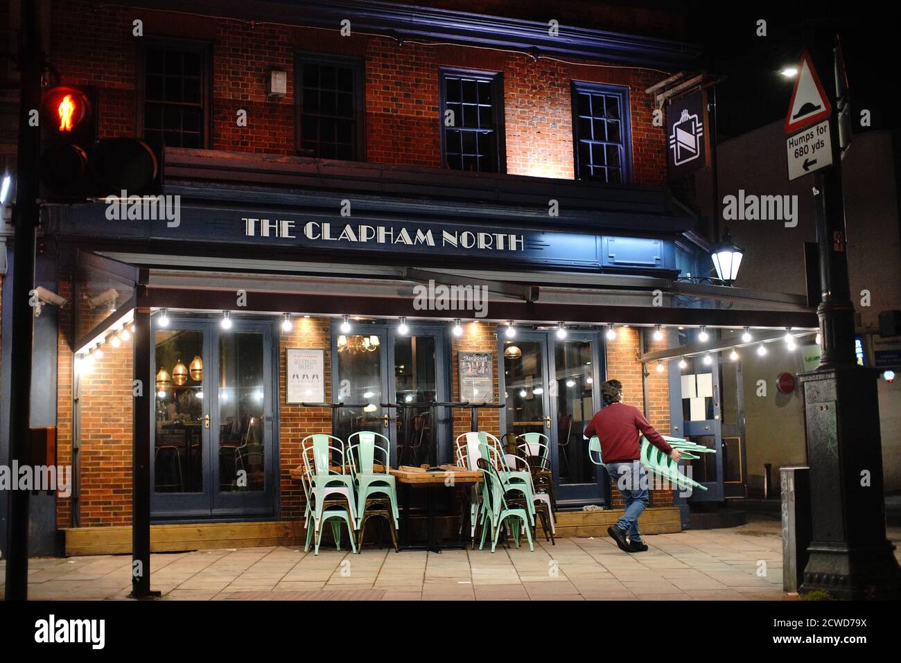 Staff pack away outside chairs at the Clapham North in Clapham, London, at 22:05hrs, after a range of new restrictions to combat the rise in coronavirus cases came into place in England. Stock Photo
