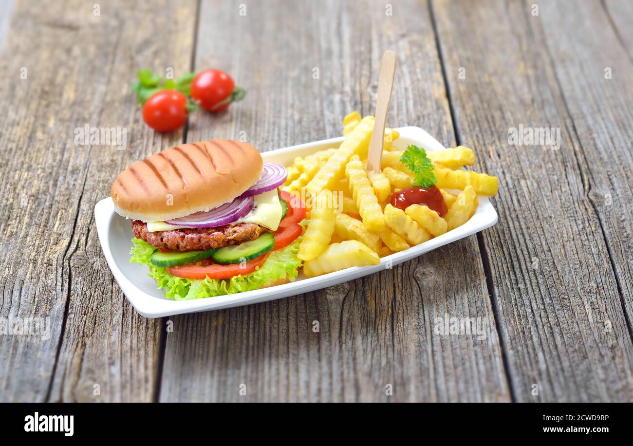 Delicious cheeseburger and chips with ketchup served in a reusable snack bar bowl on a wooden background Stock Photo
