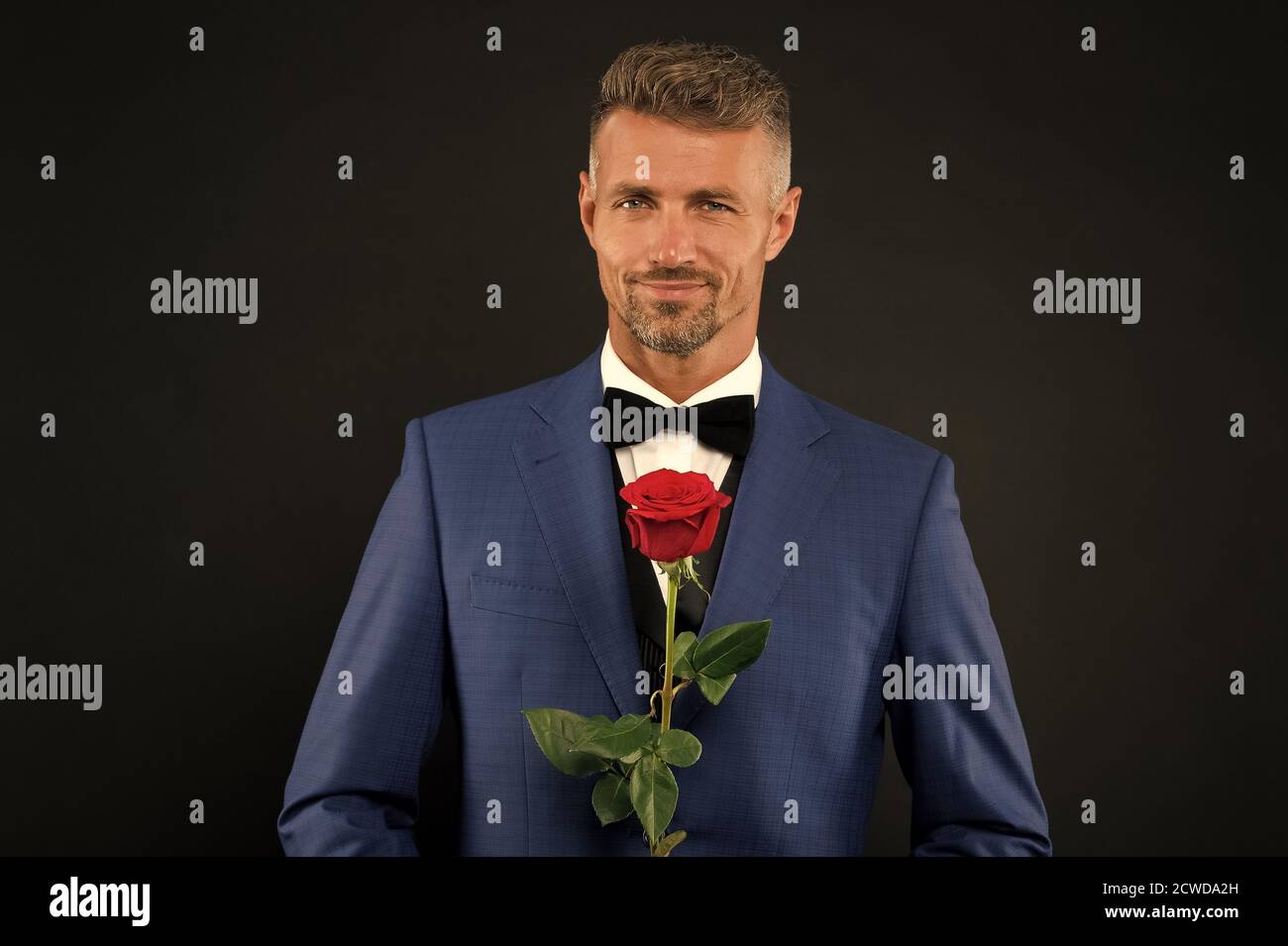 Lovely face of male. groom in tuxedo with rose. during wedding ceremony