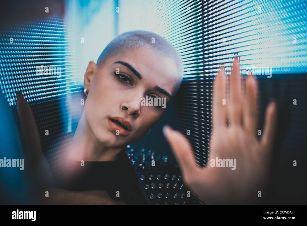 Image of a beautiful young woman posing against a led panel. Shaved head teenager with alternative look making urban portraits Stock Photo