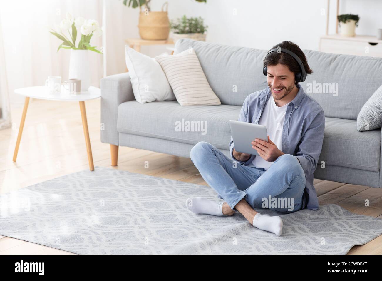 Happy young man using wireless headset and digital tablet Stock Photo