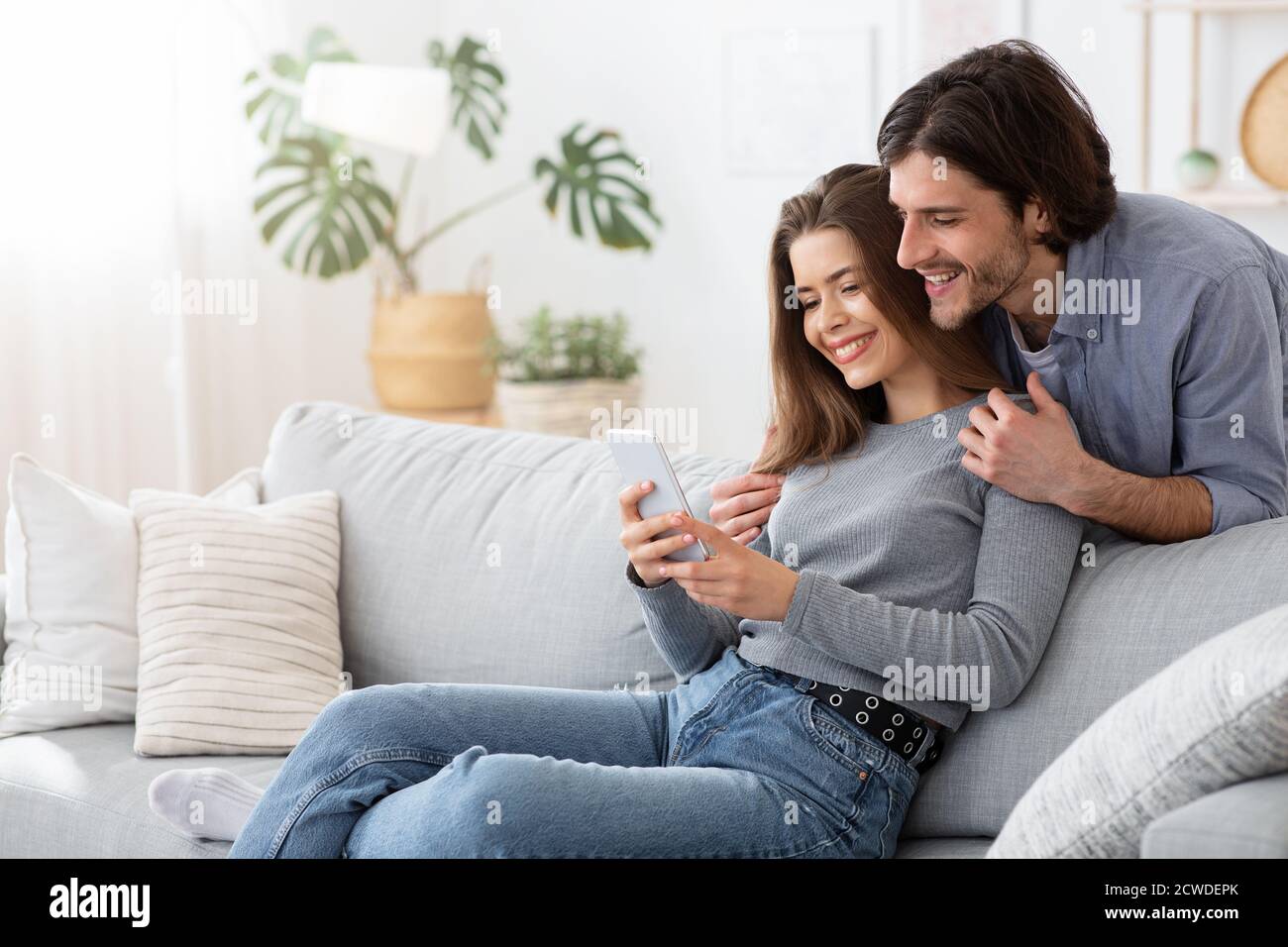 Positive young couple using mobile phone at home Stock Photo