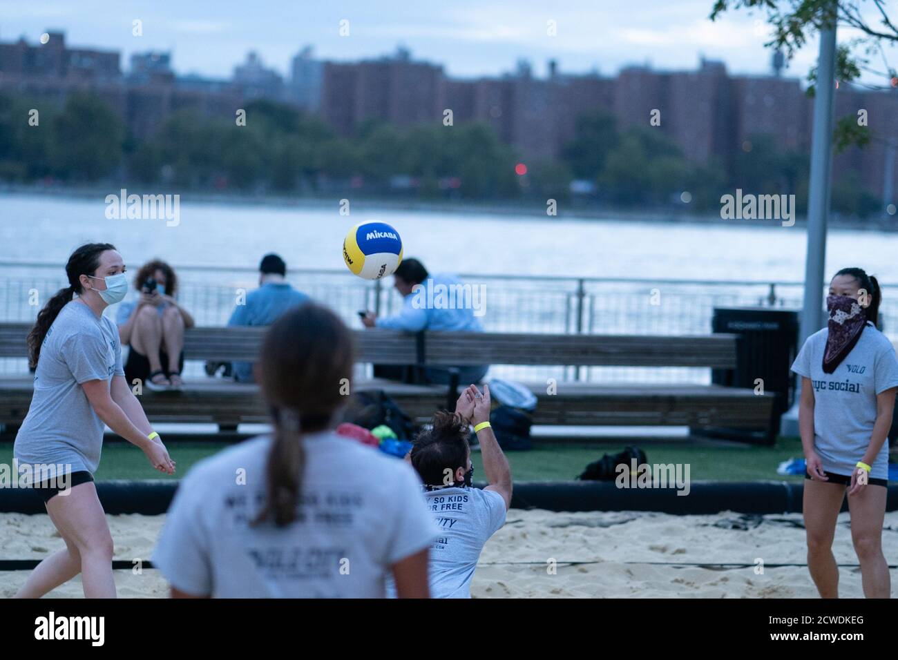People wearing face masks, playing volleyball at a competition for Volo City Kids Foundation at Domino Park in Williamsburg, Brooklyn.New York City is preparing to move into Phase 4 of re-opening following restrictions imposed to curb the coronavirus pandemic. Phase 4 involves reopening of: Zoos, pro sports, TV and movie crews. Stock Photo