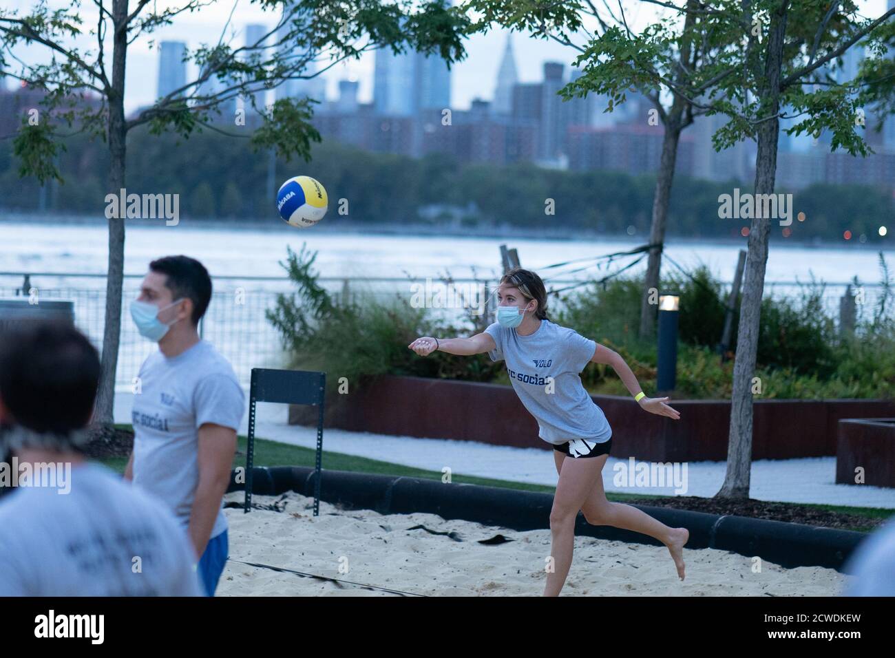 A woman wearing a face mask, playing volleyball at a competition for Volo City Kids Foundation at Domino Park in Williamsburg, Brooklyn.New York City is preparing to move into Phase 4 of re-opening following restrictions imposed to curb the coronavirus pandemic. Phase 4 involves reopening of: Zoos, pro sports, TV and movie crews. Stock Photo