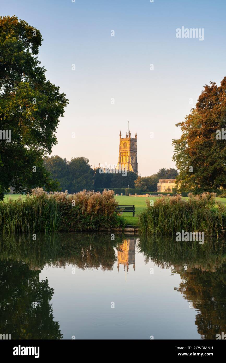 The Church of St. John the Baptist from the abbey grounds reflecting in the abbey lake at sunrise. Cirencester, Cotswolds, Gloucestershire, England Stock Photo