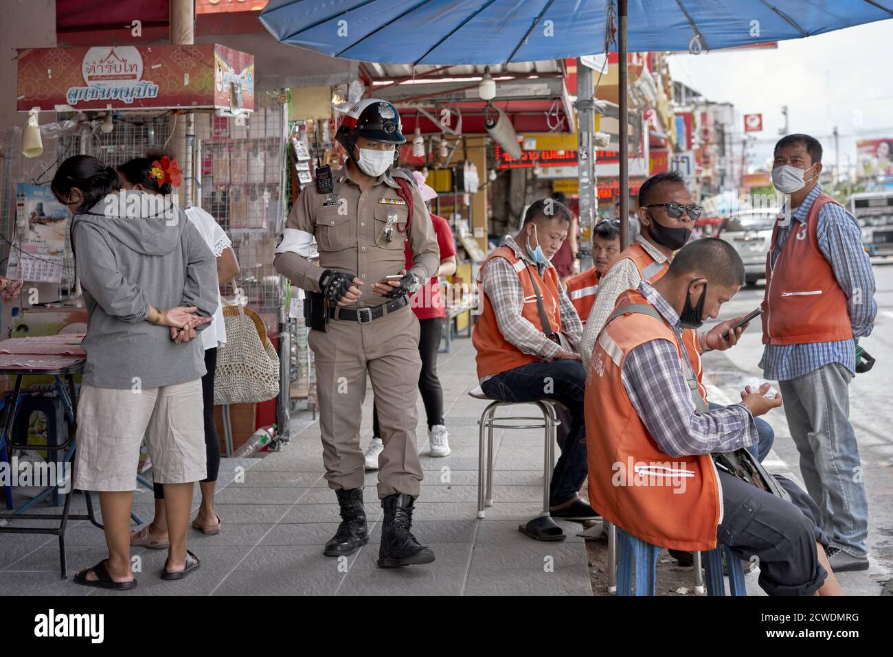 Mobile phone users. Police and taxi drivers on a Thailand sidewalk with cell phones. Stock Photo