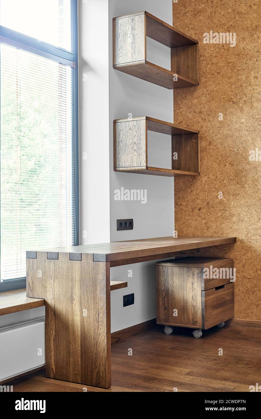 Modern furniture. Box joint solid wooden console desk with shelves against the background of the window Stock Photo