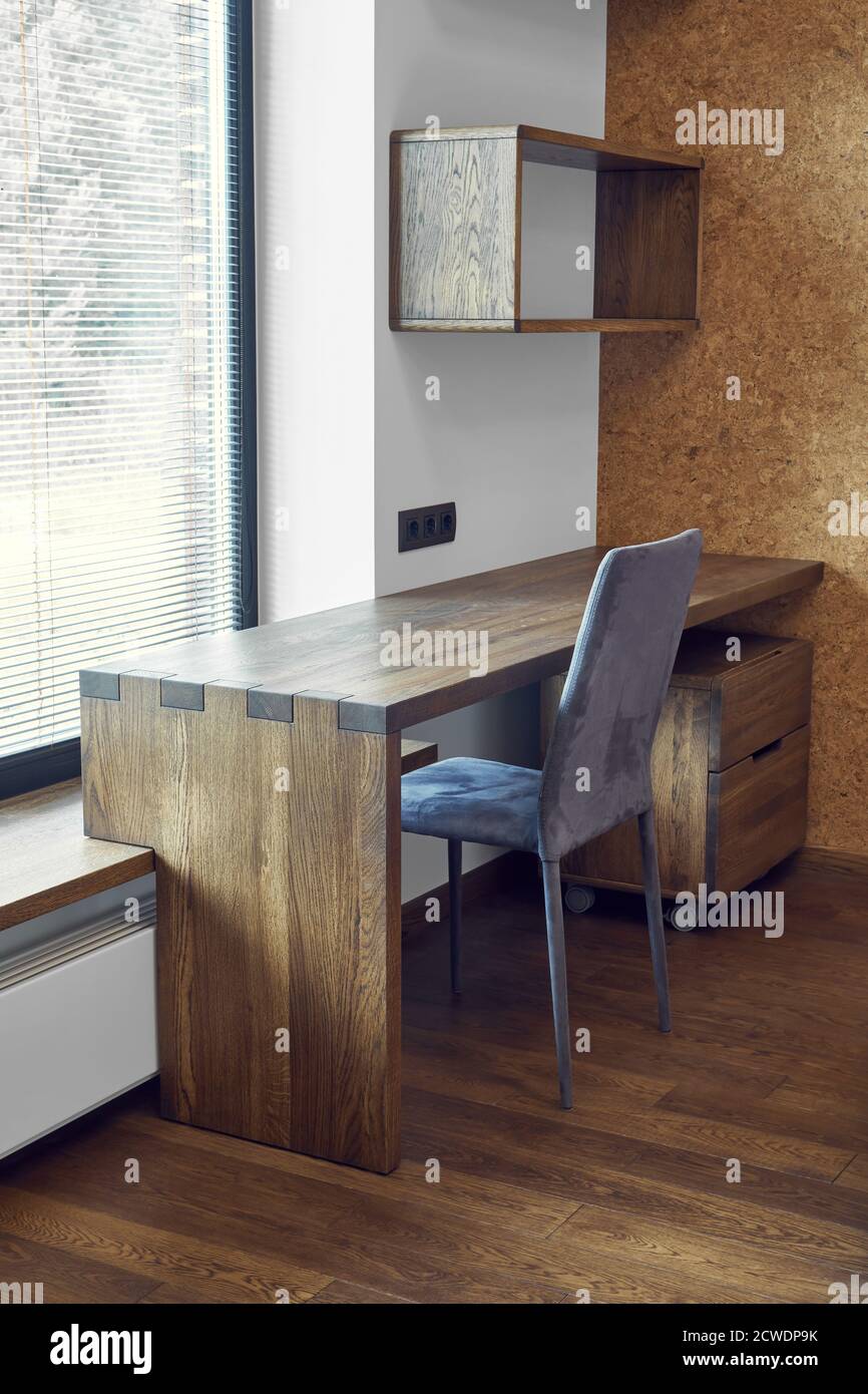 Modern furniture. Box joint solid wooden console desk with shelves against the background of the window Stock Photo