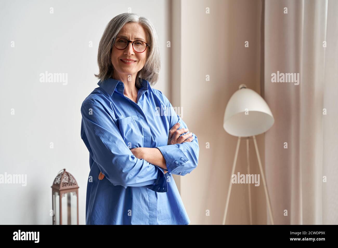 Smiling confident older lady standing arms crossed looking at camera, portrait. Stock Photo