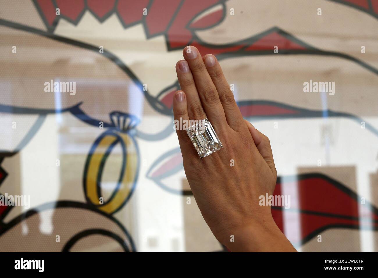 A woman displays a 100.20-carat diamond ring in front of Roy Lichtenstein's  1962 painting "The Ring (Engagement)" at a pre-auction viewing at Sotheby's  in Los Angeles, California March 25, 2015. Sotheby's says