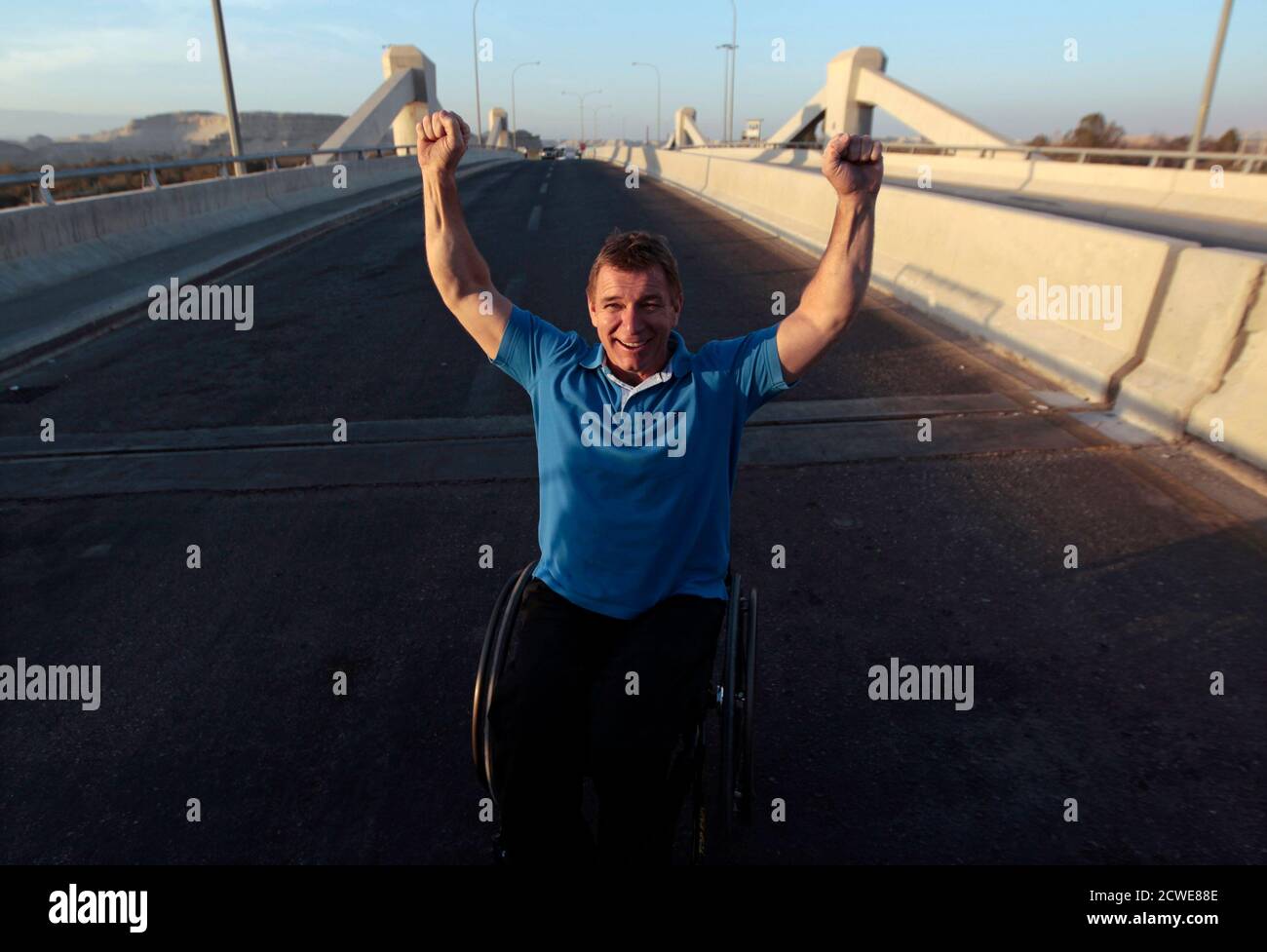 Canadian wheelchair athlete Rick Hansen raises his arms after crossing over the Israeli-controlled Allenby bridge from Jordan into the West Bank, December 1, 2010, as part of the 25th anniversary celebrations for his Man In Motion tour. Hansen symbolically crossed the bridge on Wednesday to mark his achievement of having wheeled across the bridge in 1985, as part of his international tour to raise funds for spinal cord injury research. REUTERS/Baz Ratner (WEST BANK - Tags: ANNIVERSARY SPORT IMAGES OF THE DAY) Stock Photo