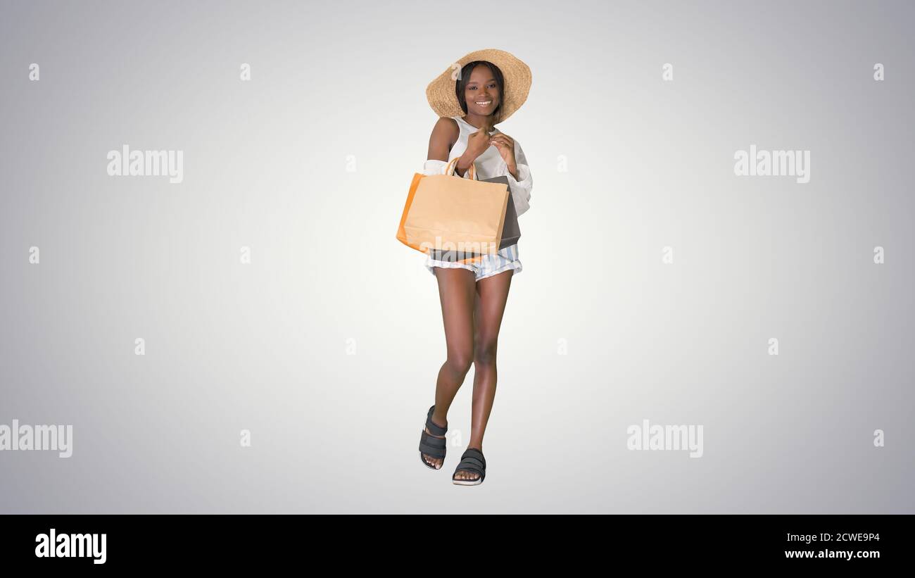 Smiling african american woman in straw hat posing with shopping Stock Photo
