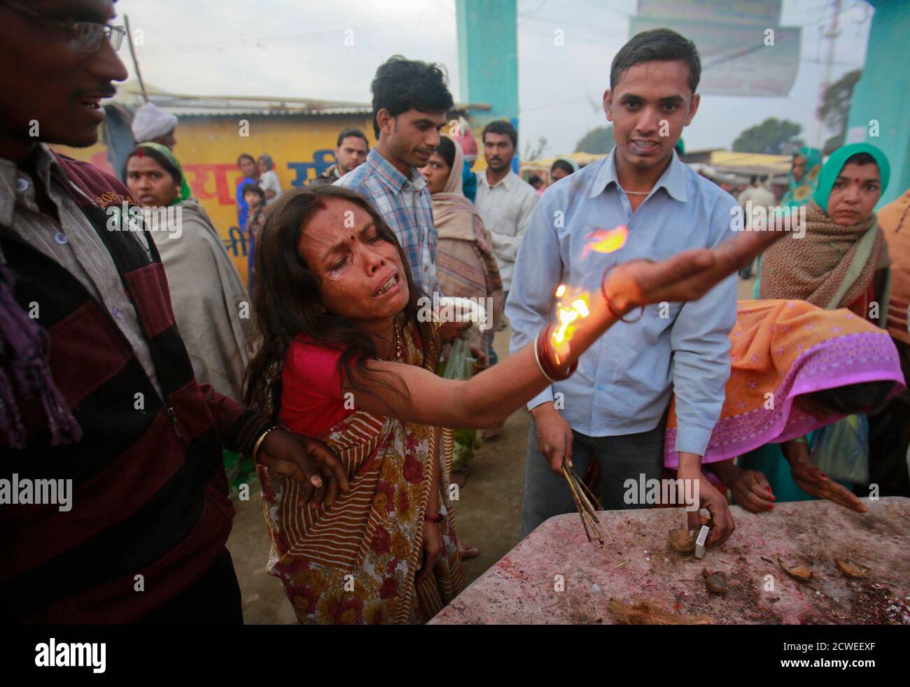 A devotee, believed to be possessed by evil spirits, cries as she performs a fire ritual on the sacred platform at Guru Deoji Maharaj temple during a ghost fair at Malajpur village in Betul district in the central Indian state of Madhya Pradesh January 27, 2013. People from across India come to this fair to be exorcised of ‘evil spirits’. They are usually brought by relatives and they are most often women. The exorcism involves running around the temple courtyard to make the 'ghost' weak then being beaten by a priest with a broom. Picture taken January 27, 2013. REUTERS/Danish Siddiqui (INDIA  Stock Photo