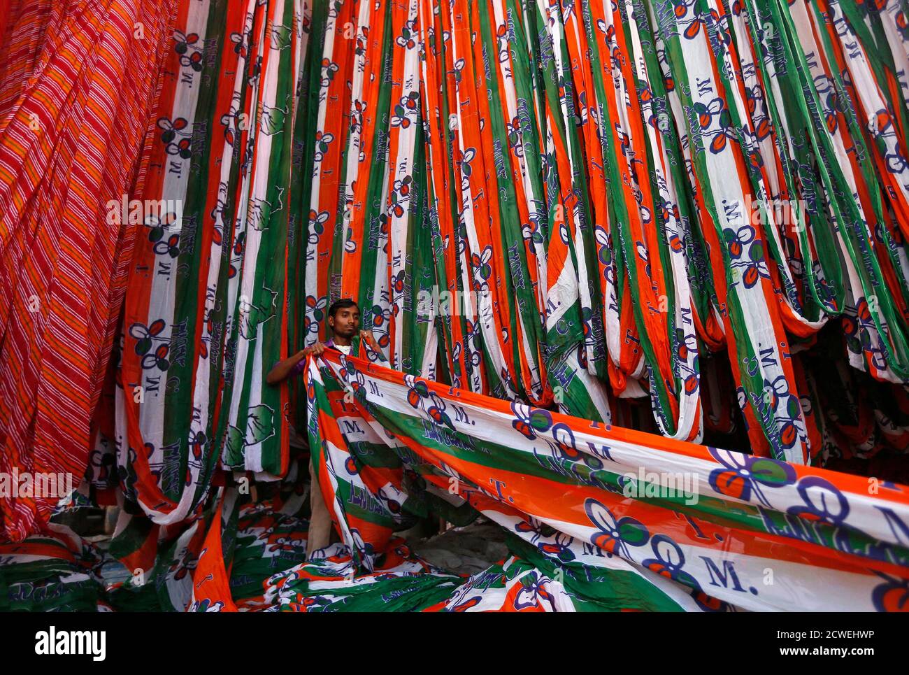 details Evacuatie voor A worker pulls out a roll of cloth to be made into flags for the Trinamool  Congress (TMC) party, while it is put out to dry at a flag manufacturing  factory in