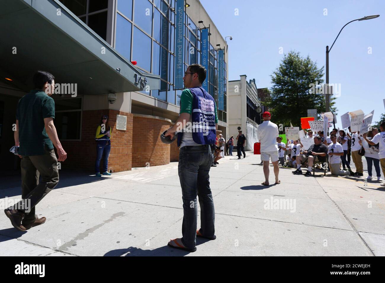 A volunteer stands near abortion protesters in front of a Planned Parenthood clinic in Boston, Massachusetts, June 28, 2014. Massachusetts is beefing up security around abortion clinics and scrambling for a legal fix after the U.S. Supreme Court voided the state's buffer zone law that kept protesters 35 feet away, saying it violated freedom of speech. Boston, Worcester and Springfield, the state's largest cities, have deployed extra police to clinics, and abortion-provider Planned Parenthood said it was training new 'patient escorts' to help women through protests if needed. REUTERS/Dominick R Stock Photo