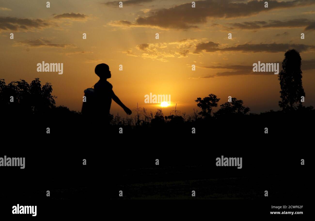 A boy carries a bucket at sunset in the village of Kogelo, west of Kenya's capital Nairobi, July 15, 2015. U.S. President Barack Obama visits Kenya and Ethiopia later this month. His ancestral home of Kogelo is home to Sarah Hussein Obama, his step-grandmother. The Kenyan village, burial place of Obama's father, features an open-pit goldmine, a pork butcher's, a school named after their most famous son and outdoor market stalls. Villagers get around by motorbike taxi or on foot while a donkey-cart transports water. Children, some of them named Obama in honour of the President, walk to and from Stock Photo