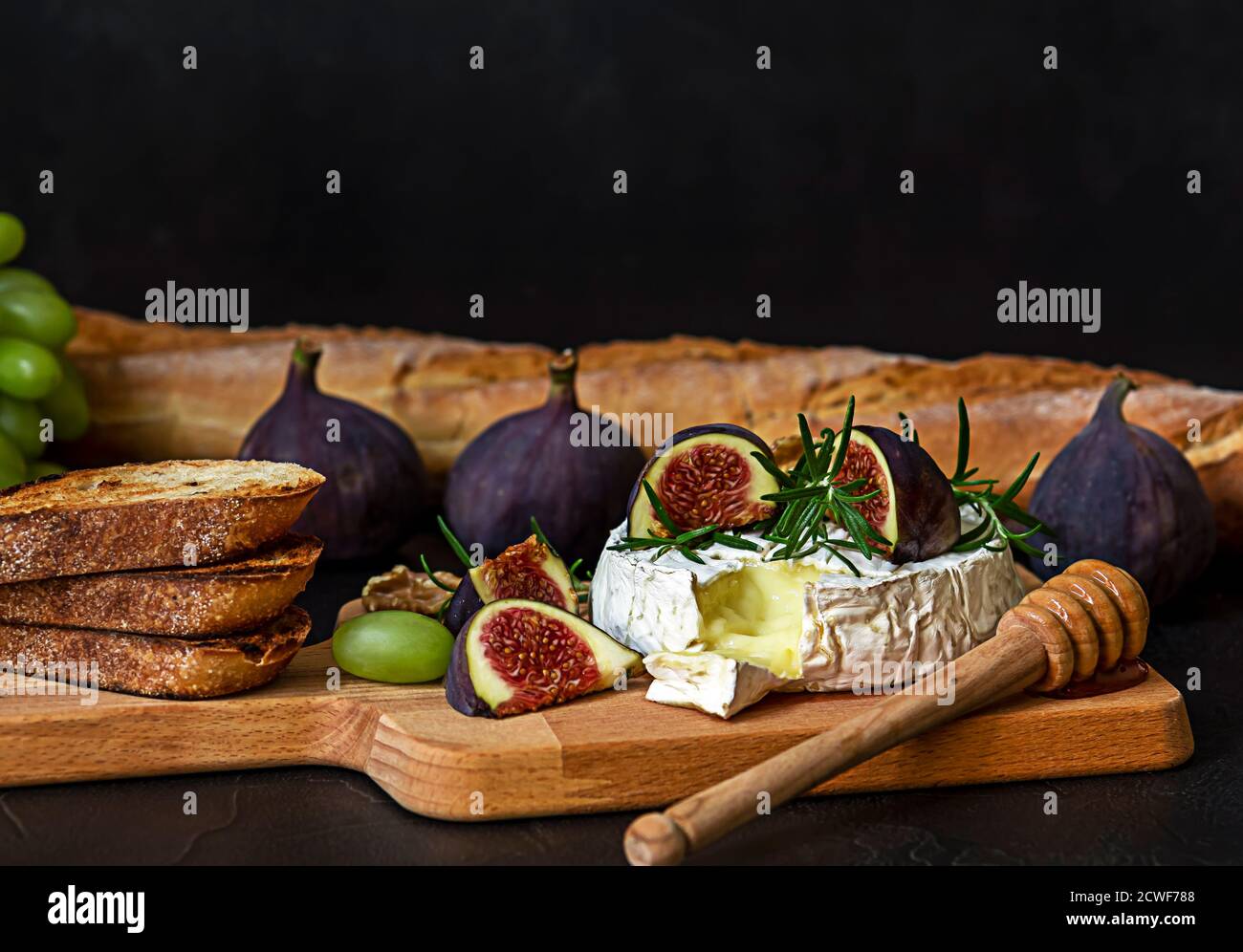 Oven baked Camembert cheese with honey, figs, and fresh bread Stock