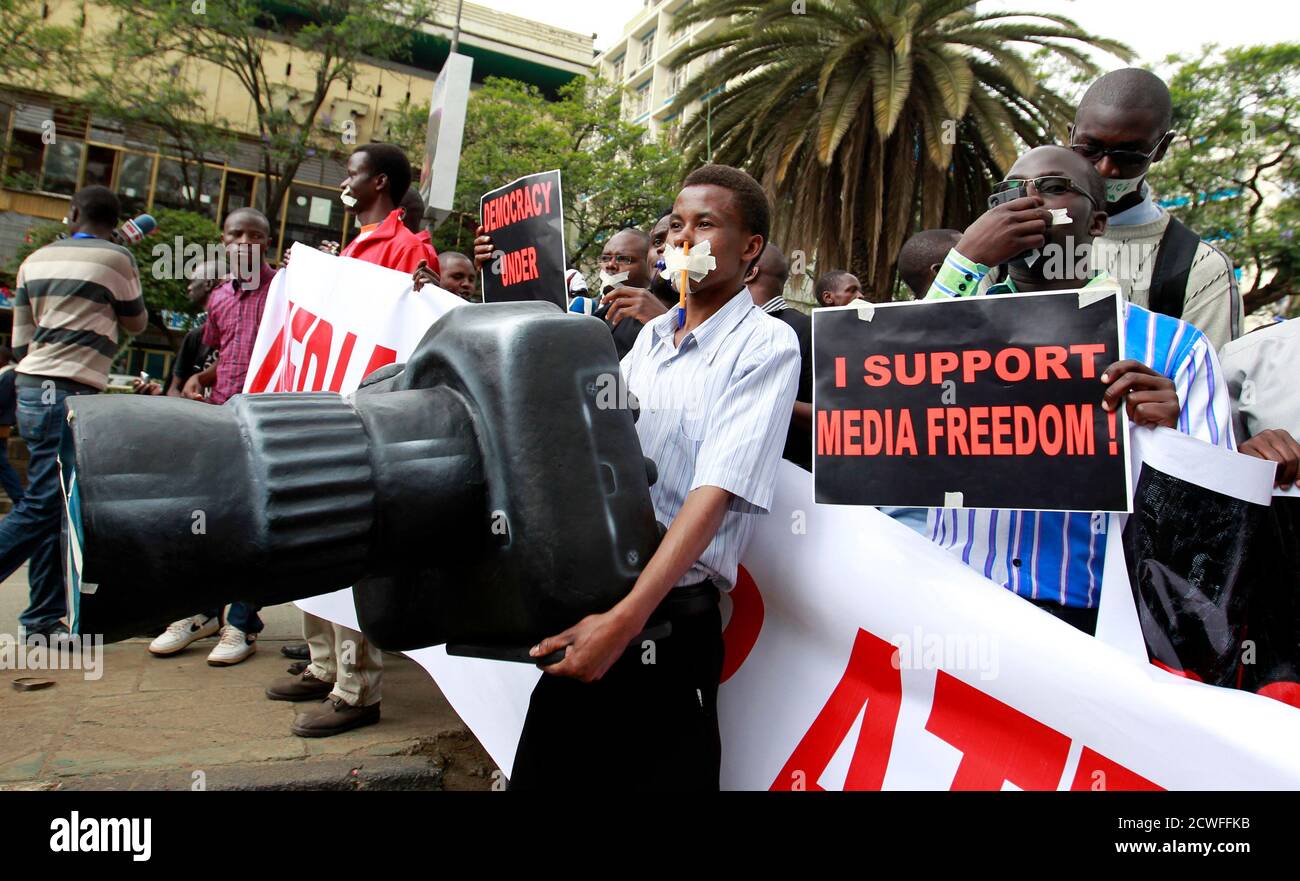 A Kenyan journalist carries a plastic replica of a camera as he participates in a protest along the streets of the capital Nairobi, December 3, 2013. Members of the Kenyan media marched in a peaceful protest to denounce the new draconian laws tabled by parliament. Kenya's president vetoed a bill that would have imposed fines and restrictions on journalists, saying it was unconstitutional, the first time he has used his power to reject legislation. Critics say rules laid down in the bill would curb investigative reports on corruption that plagues Kenyan public life and some media groups threate Stock Photo