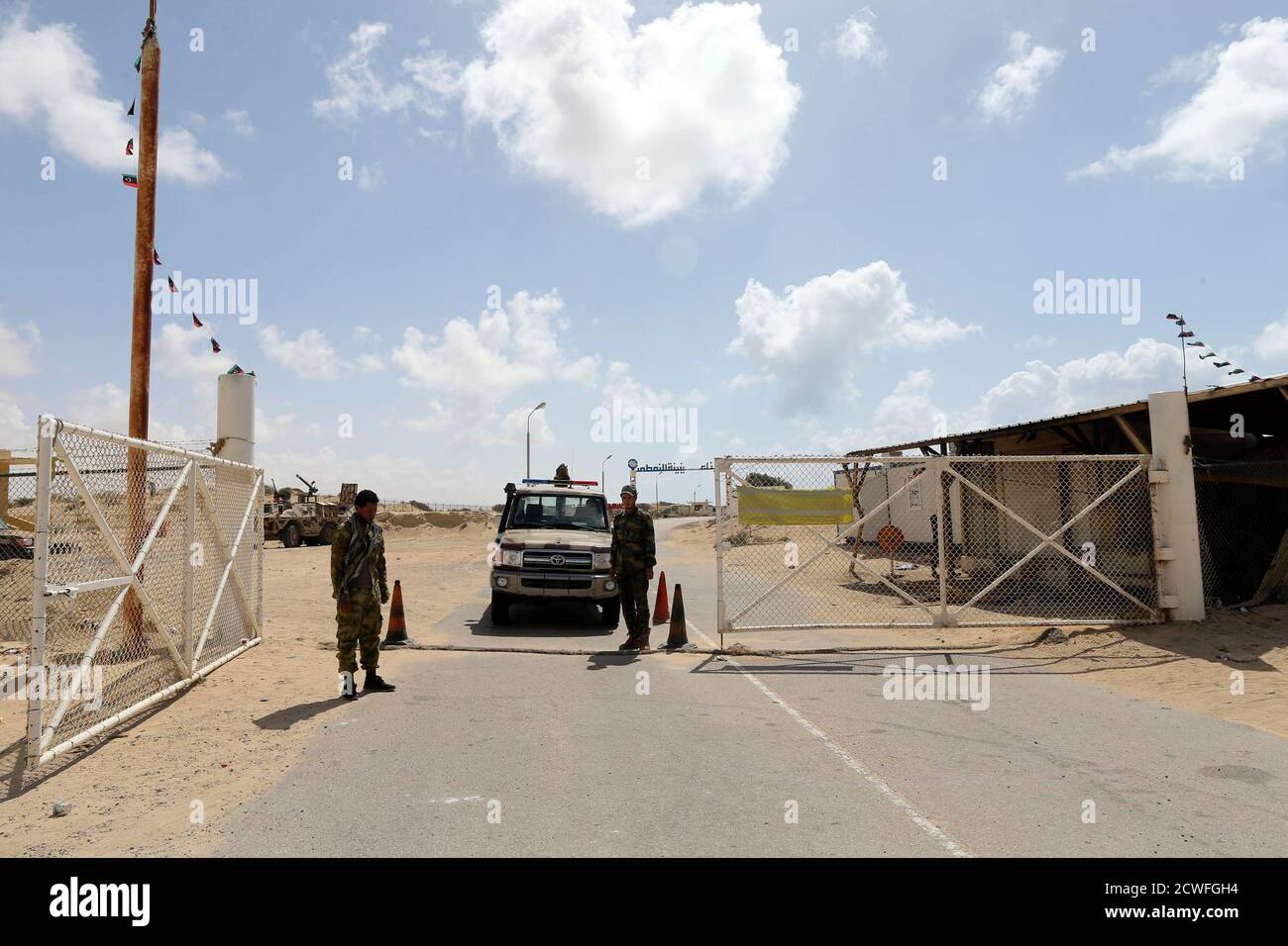 Security officers stand guard at the gates of the Zueitina oil terminal in Zueitina, west of Benghazi April 7, 2014. Libya's Zueitina oil port prepared on Monday to load crude on tankers after the government reached a deal with rebels to reopen four terminals that insurgents have occupied since summer. The federalist rebels agreed on Sunday to end gradually their eight-month blockade of Zueitina, Hariga, Ras Lanuf and Es Sider ports, which account for around 700,000 barrels per day of the OPEC country's crude exports. REUTERS/Esam Omran Al-Fetori (LIBYA  - Tags: POLITICS ENERGY BUSINESS) Stock Photo