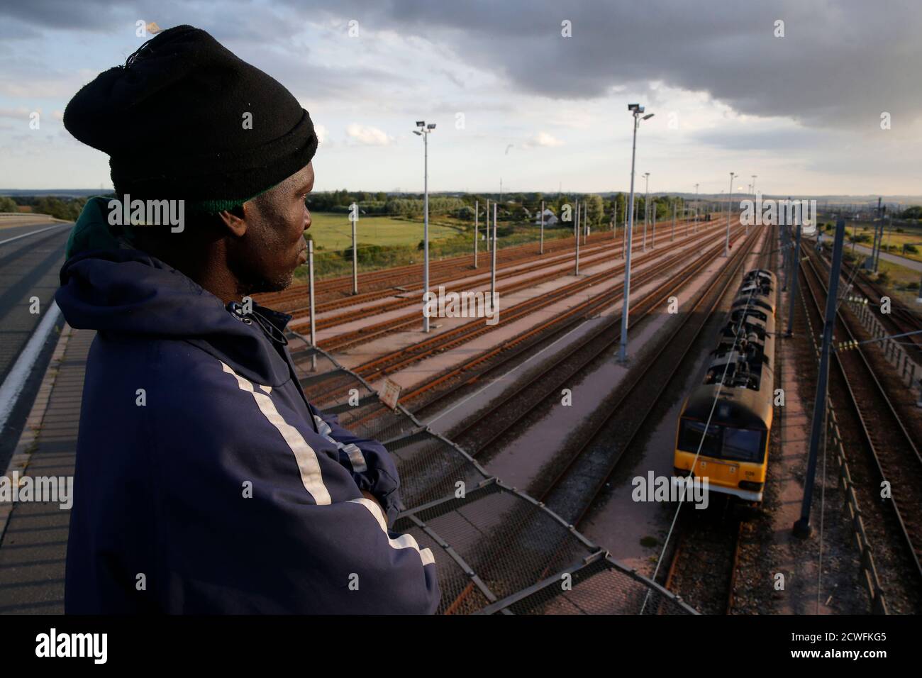 A Migrant From Rwanda Who Gave His Name As Alex Aged 35 And Is The Father Of Two Children Stands On An Overpass As He Watches A Train Pass On Tracks Below A Migrant From Rwanda Who Gave His Name As Alex Aged 35 And Is The Father Of Two Children Stands On An Overpass As He Watches A Train Pass On Tracks Below