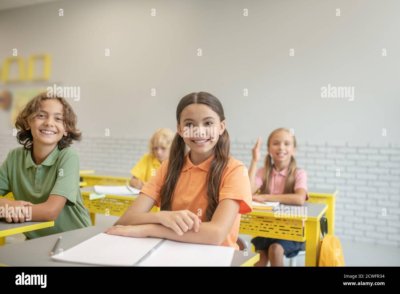 Two schoolchildren sitting at the desk and smiling Stock Photo - Alamy