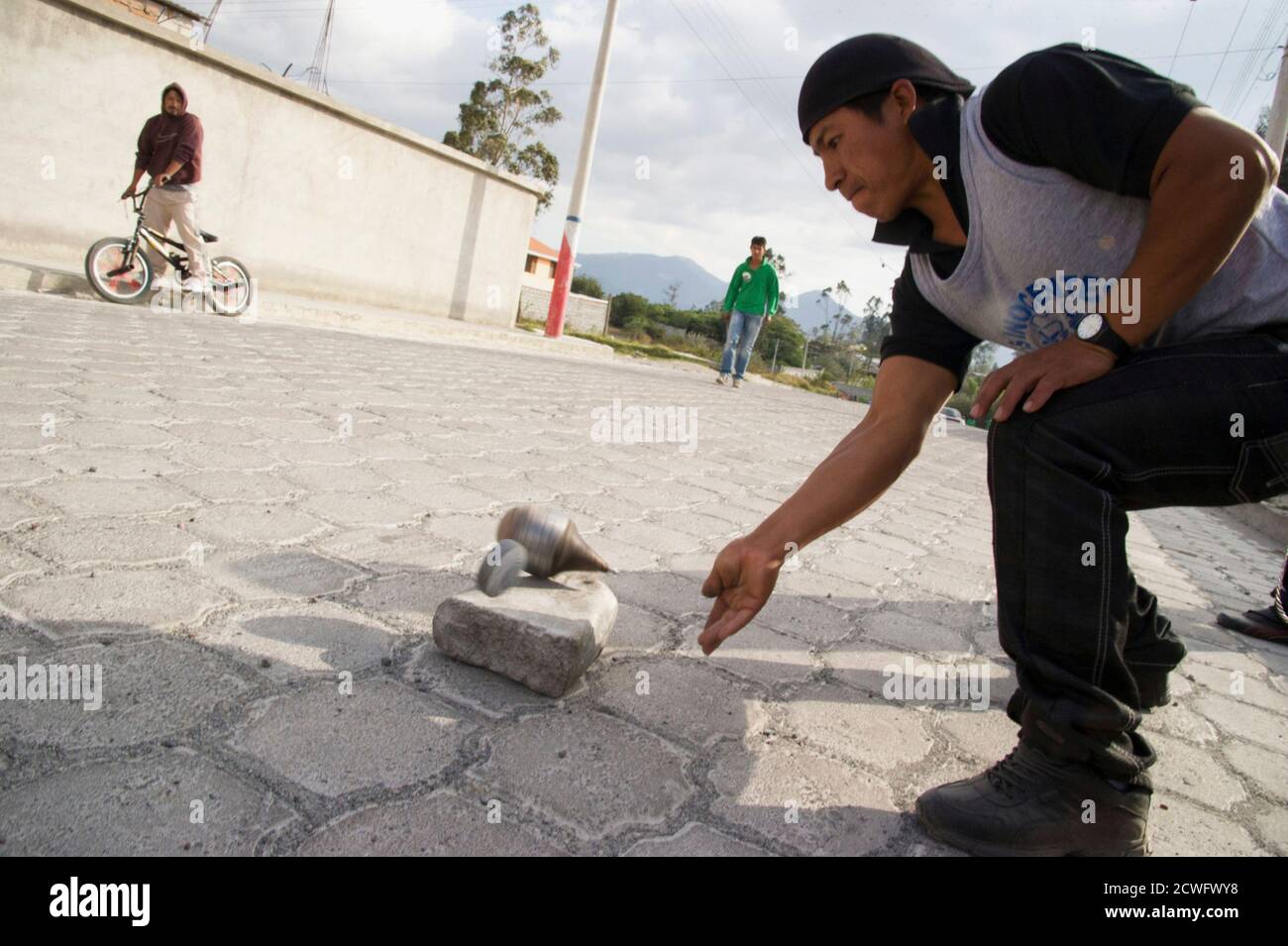 A resident hits his "trompo gigante" to play a "cave" during a game of "trompo gigante" in Cotacachi, about 120 km (75 miles) north of Quito September 8, 2012. Fifteen teams, each made up of 10 members, representing different neighbourhoods of the village compete to see who can hit "la bola" from the start point in the main park to the finishing point about 8-10 km (5-6.2 miles) away through the streets of Cotacachi with the least number of "caves", or hits. The game, an annual event, runs from August to November and was started in the village famous for its leather 17 years ago. The contestan Stock Photo