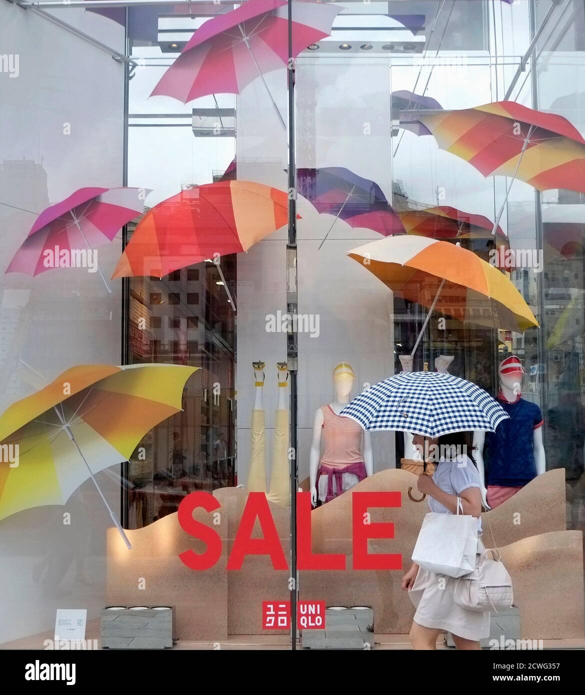A woman walks past a Fast Retailing's Uniqlo casual clothing store in Tokyo July 10, 2014. Japan's Fast Retailing Co , operator of the Uniqlo casualwear brand, on Thursday posted a 9.9 percent rise in operating profit in the nine months through May, as its overseas Uniqlo sales showed strong growth. REUTERS/Toru Hanai (JAPAN - Tags: BUSINESS FASHION) Stock Photo