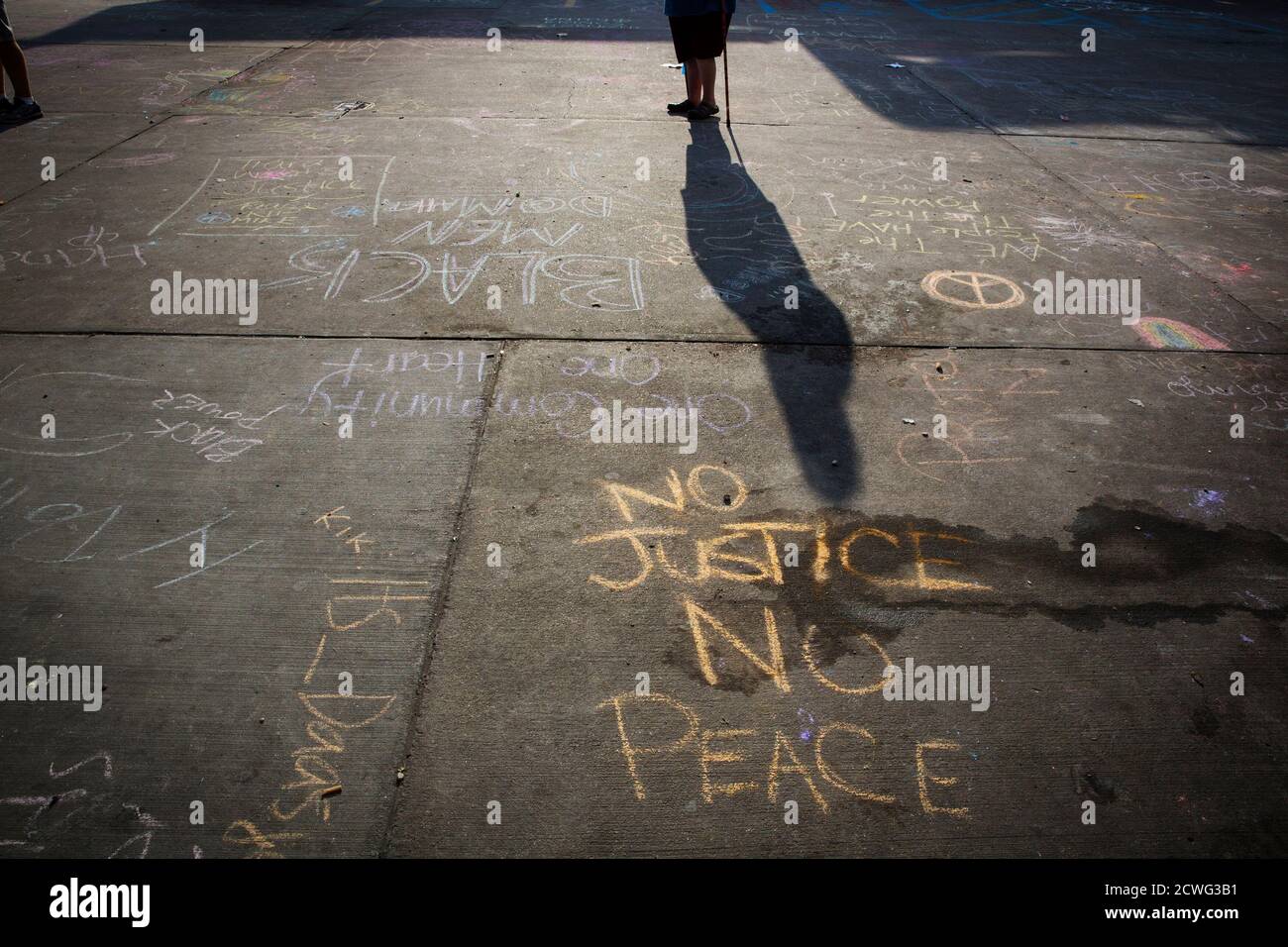 A man with a walking stick passes protest messages written in a parking lot before the announcement of the name of the officer involved in the shooting of Michael Brown in Ferguson, Missouri August 15, 2014. Police Chief Thomas Jackson on Friday identified Darren Wilson as the police officer who fatally shoot an unarmed black teenager, which led to days of sometimes-violent demonstrations. Jackson announced the name at a press conference held near a QuikTrip convenience store that had been burned amid protests over the shooting of Brown, 18, last Saturday. REUTERS/Lucas Jackson (UNITED STATES Stock Photo