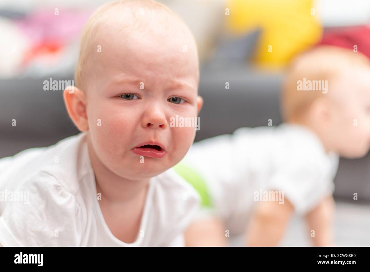 Little unhappy baby crying on the floor in his room Stock Photo