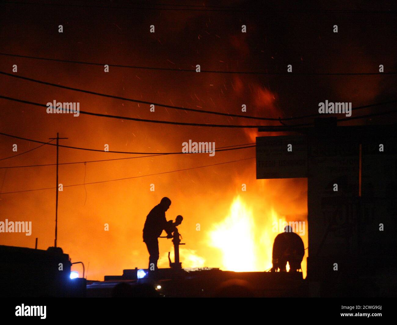 Two Albanian firefighters try to put out a huge fire, which started at a fireworks warehouse in Tirana November 21, 2011. Some shops and warehouses nearby burnt to the ground, but there were no deaths or injuries, according to a police spokesman. REUTERS/Arben Celi (ALBANIA - Tags: DISASTER TPX IMAGES OF THE DAY) Stock Photo