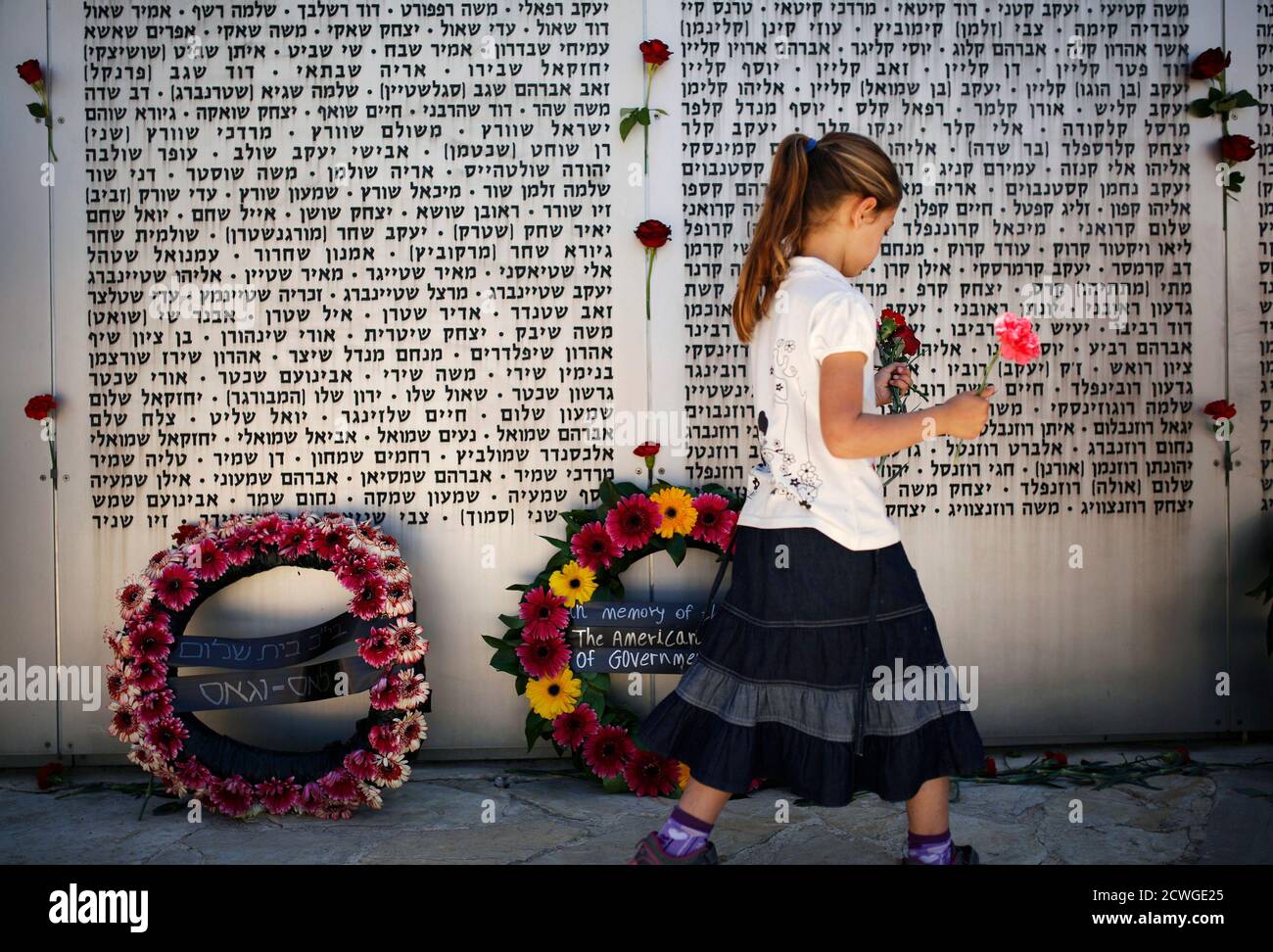 A girl holds flowers as she walks in front of a memorial wall, engraved with names of fallen Israeli soldiers, after a ceremony marking Memorial Day at the Israeli army's Armoured Corps' Memorial in Latrun, near Jerusalem April 15, 2013. Israel on Monday marks Memorial Day to commemorate its fallen soldiers. REUTERS/Amir Cohen (ISRAEL - Tags: ANNIVERSARY MILITARY POLITICS CONFLICT TPX IMAGES OF THE DAY) Stock Photo
