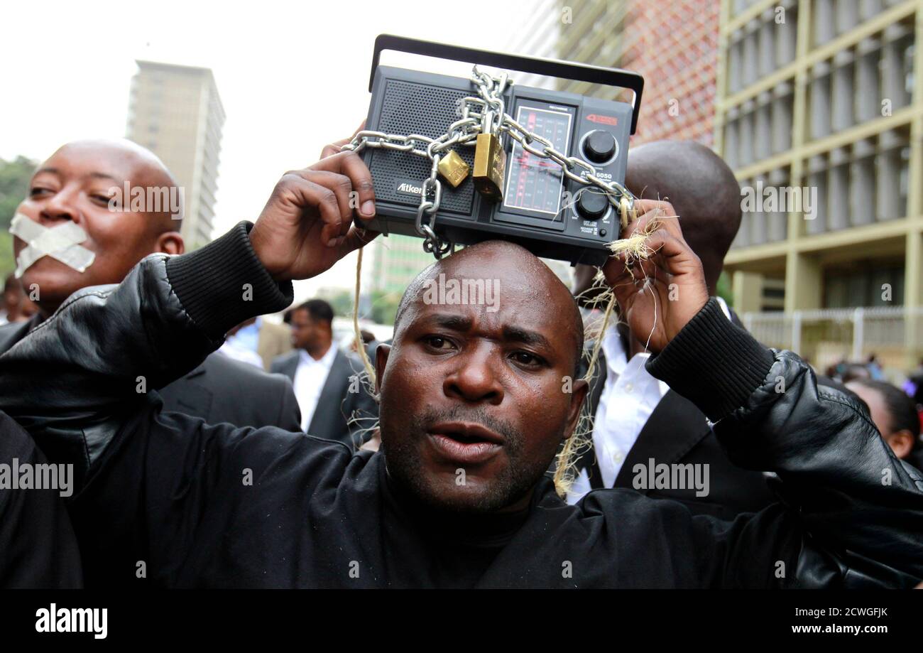 A Kenyan journalist carries a radio wrapped in a chain as he participates in a protest along the streets of the capital Nairobi, December 3, 2013. Members of the Kenyan media marched in a peaceful protest to denounce the new draconian laws tabled by parliament. Kenya's president vetoed a bill that would have imposed fines and restrictions on journalists, saying it was unconstitutional, the first time he has used his power to reject legislation. Critics say rules laid down in the bill would curb investigative reports on corruption that plagues Kenyan public life and some media groups threatened Stock Photo