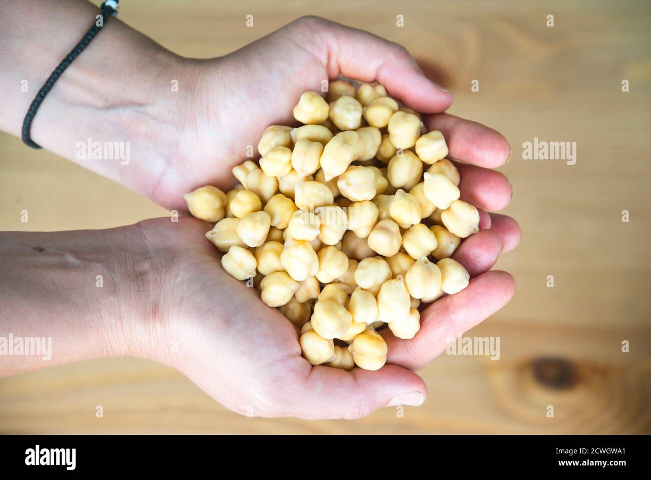Raw chickpeas in woman's hands, top view Stock Photo
