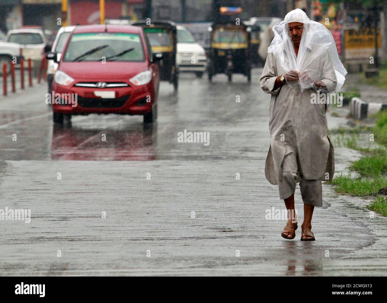 A man covers himself with a polythene sheet as it rains in Srinagar August  4, 2012. A moderate rainfall in Srinagar since Friday evening brought down  temperatures from 34 degrees Celsius (93