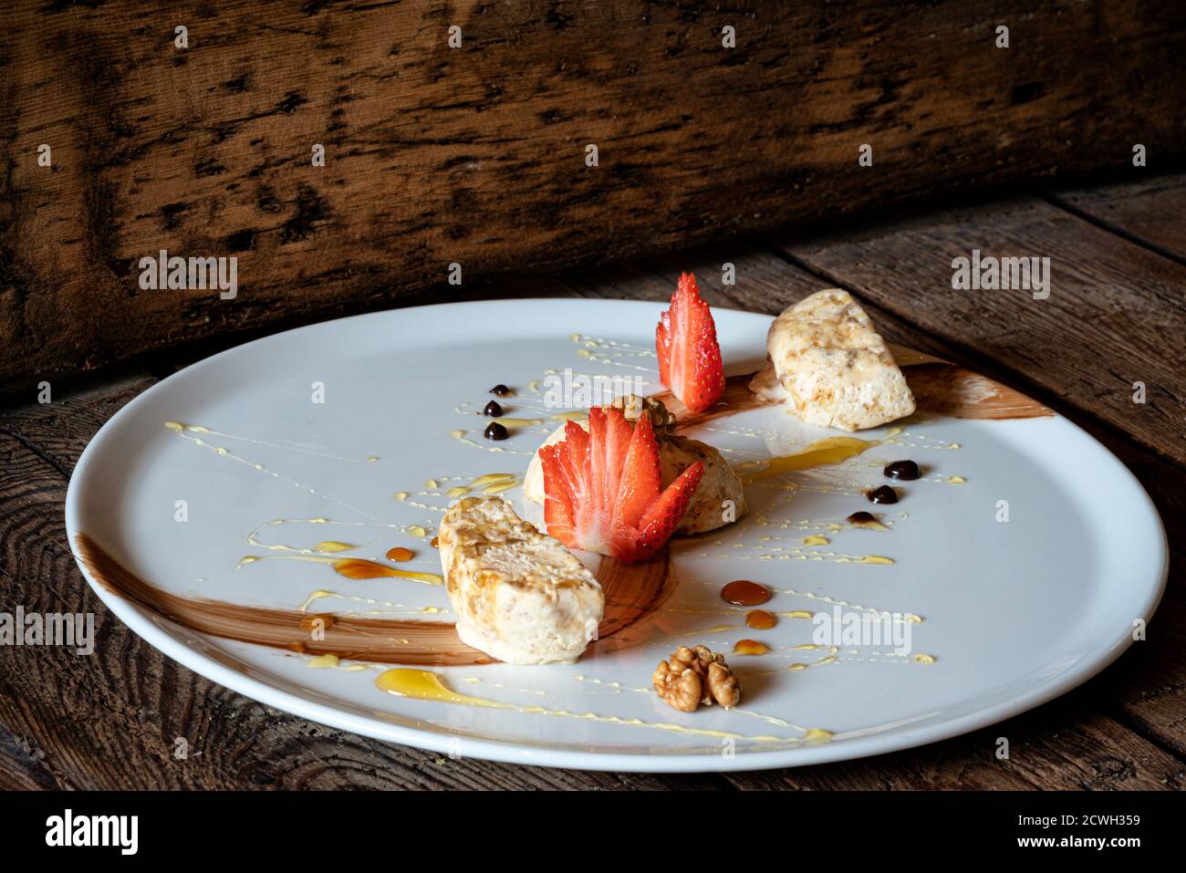 Italian torroncino semifreddo dessert made of nougat garnished with strawberries and walnuts Stock Photo