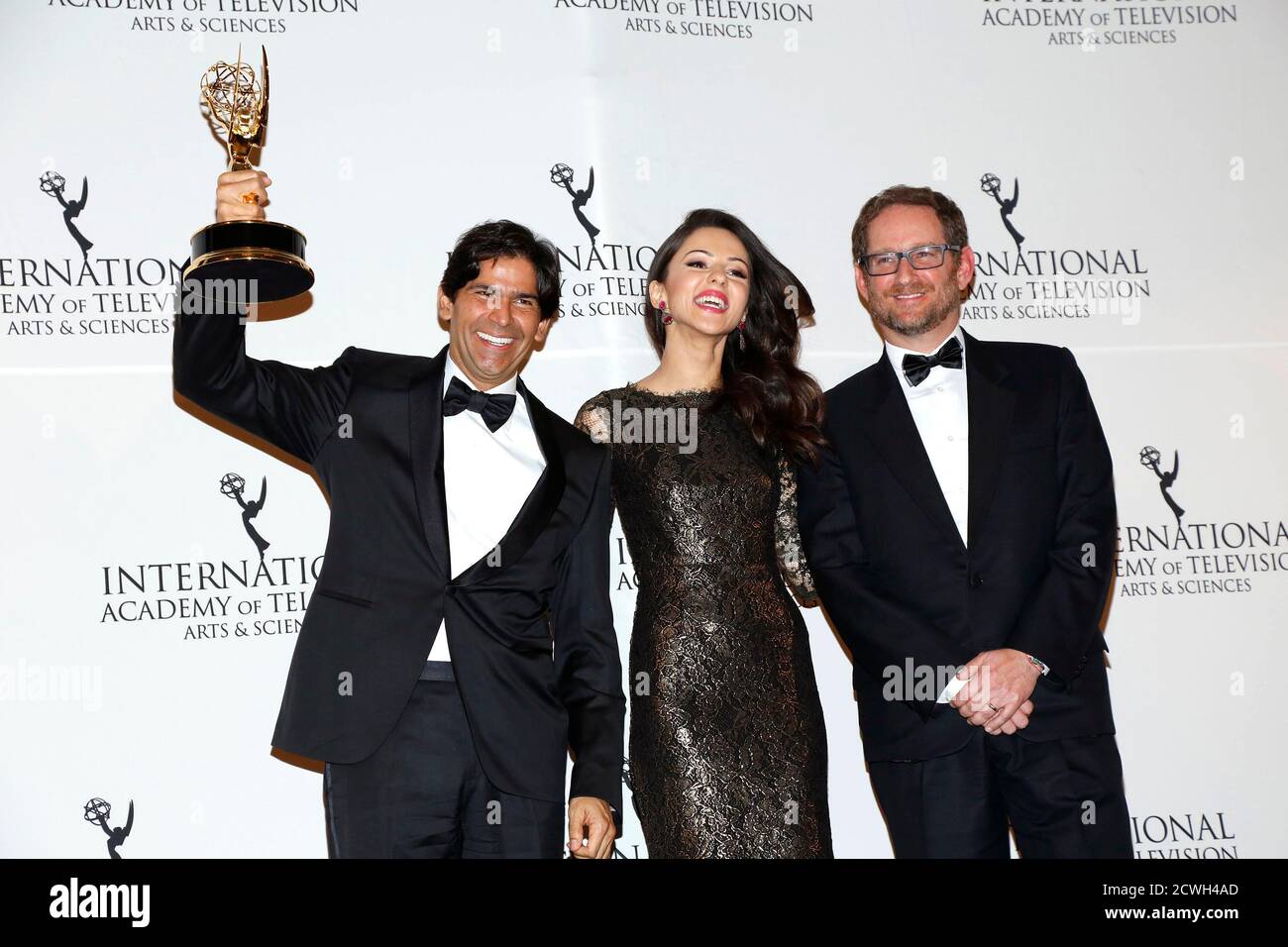 President of Production Worldwide Distribution Division Marcos Santana and EVP Scripted Programming and General Manager at Telemundo Joshua Mintz (R) pose backstage with their Non-English Language US Primetime award for for 'El Senor de los Cielos', with presenter Annet Mahendru at the 42nd International Emmy Awards in New York November 24, 2014. REUTERS/Andrew Kelly (UNITED STATES - Tags: ENTERTAINMENT) Stock Photo