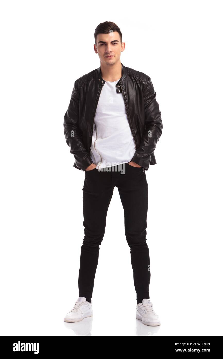 relaxed young man in leather jacket standing with hands in pockets and