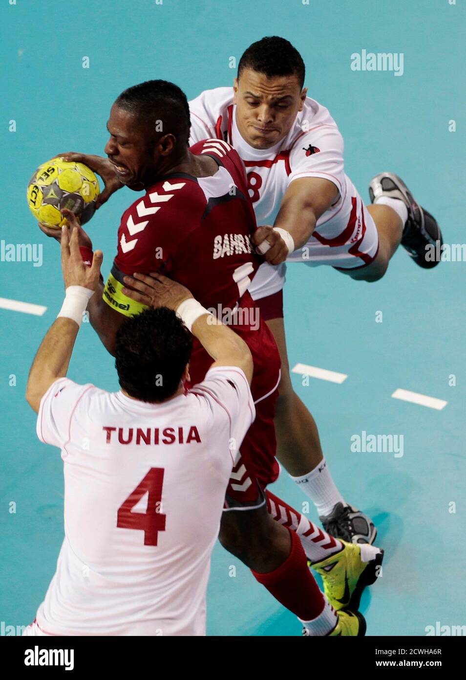 Bahrain's Saeed Jawher (C) tries to make a pass between Tunisia's Benali  Youssef and Mohamed Ali Bhar (4) during their men's handball game at the  Arab Games in Doha December 12, 2011.
