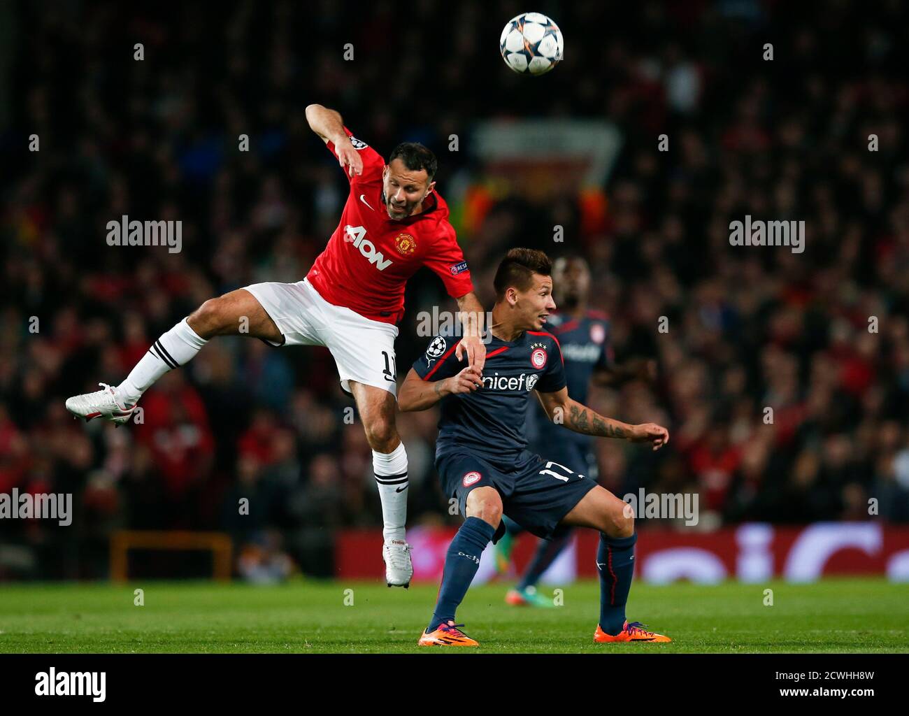 Manchester United's Ryan Giggs (L) jumps for the ball against Olympiakos'  Hernan Perez during their Champions League soccer match at Old Trafford in  Manchester, northern England, March 19, 2014. REUTERS/Phil Noble (BRITAIN -