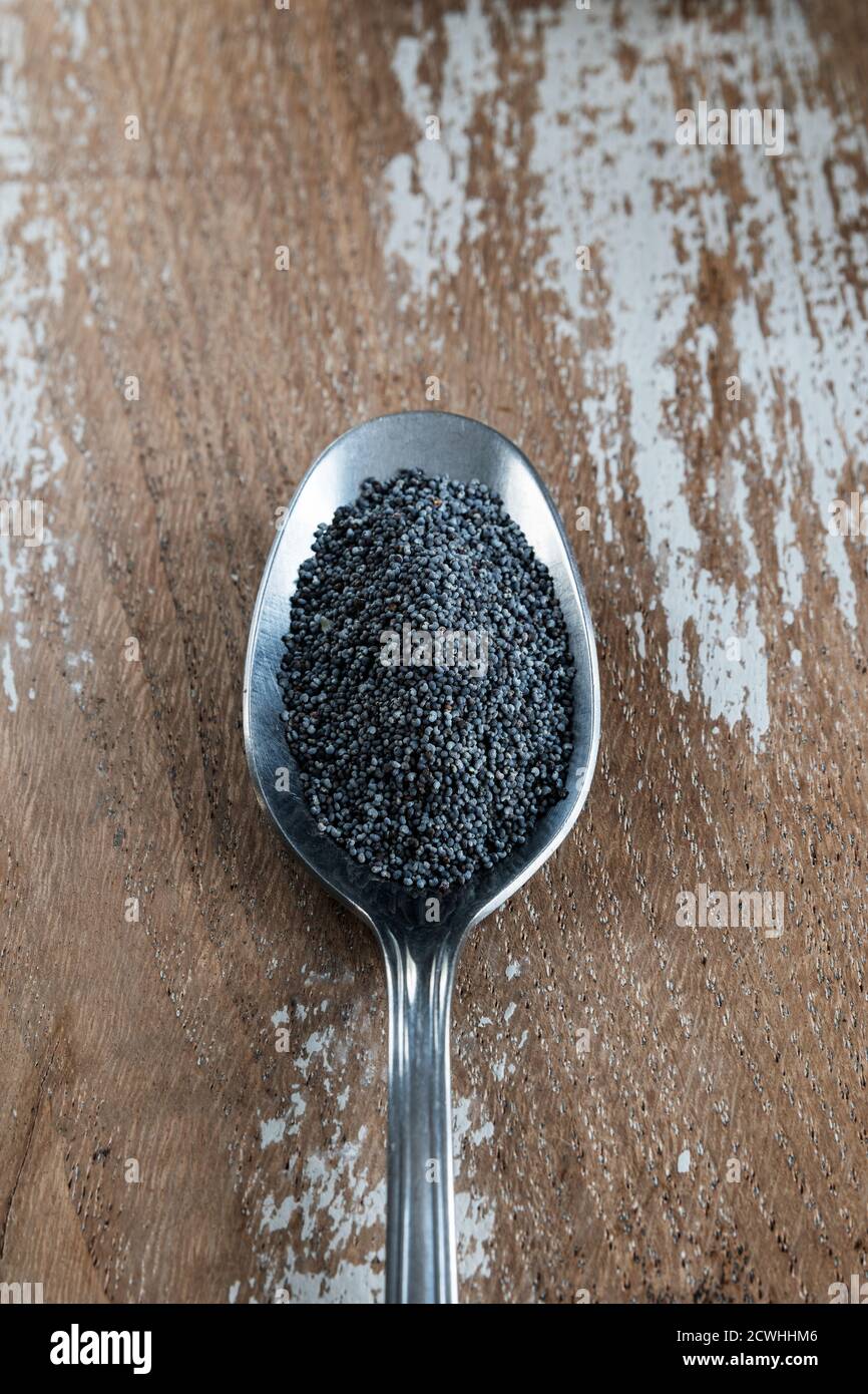 Poppy seeds in a spoon on rustic background Stock Photo