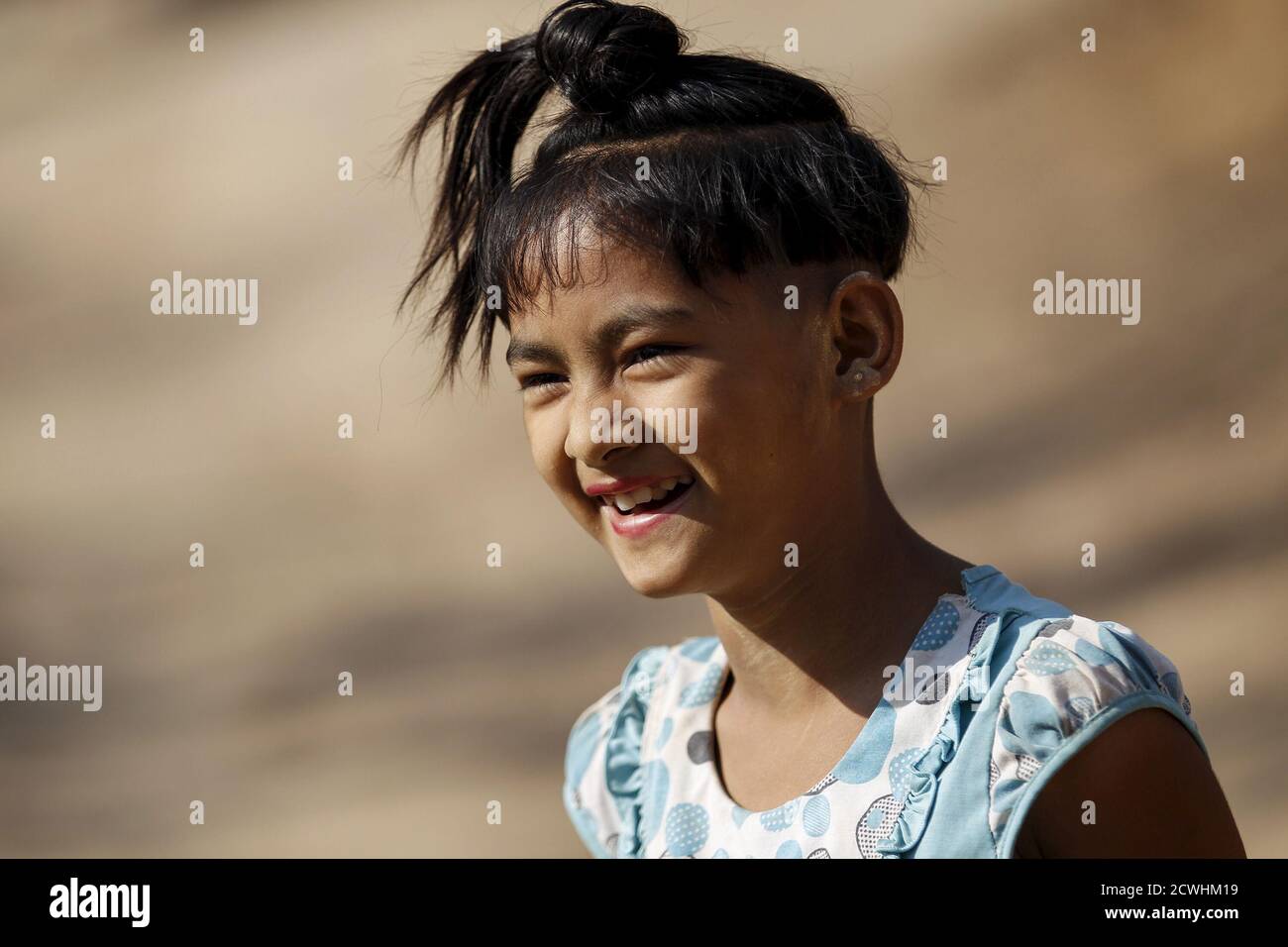 That Mon Kaw, a nine-year-old girl, sports an ancient hairstyle known as Sanyitwine while smiling at Sat Sat Yo village in Nyaung Oo township, near Myanmar's ancient city Bagan April 17, 2015. That Mon Kaw, a nine-year-old girl, sports an ancient hairstyle known as Sanyitwine while smiling at Sat Sat Yo village in Nyaung Oo township, near Myanmar's ancient city Bagan April 17, 2015.