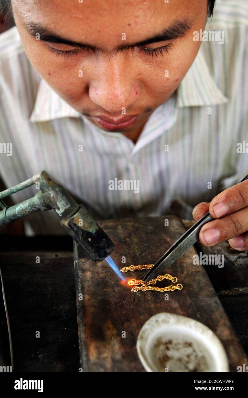 A goldsmith crafts a gold chain at a jewellery workshop in the northern Myanmar city of Myitkyina February 26, 2012. Picture taken February 26, 2012. REUTERS/Staff (MYANMAR - Tags: BUSINESS COMMODITIES) Stock Photo