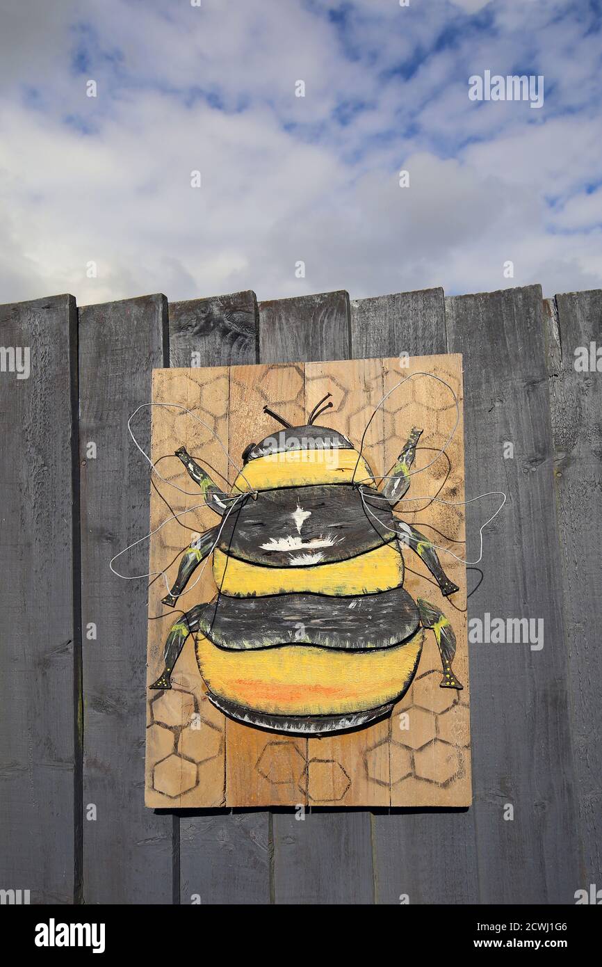 Painted bee with wire wings mounted on a wooden fence Stock Photo