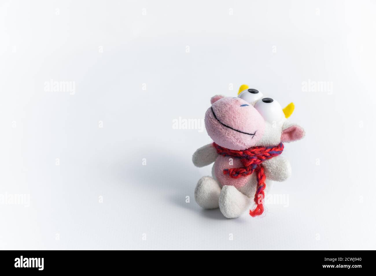 A cute toy for funny children's games. Children's soft toy bull in a red scarf, on a white background. The symbol of the new 2021. Close-up.Copy space Stock Photo