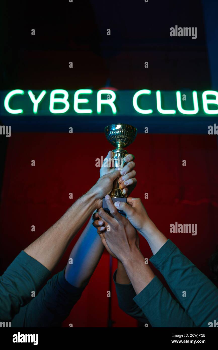 Closeup of group of gamers holding cup together they winning the